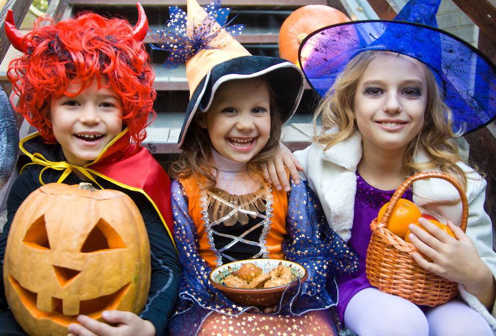 Children trick or treating dressed as two witches and a devil.
