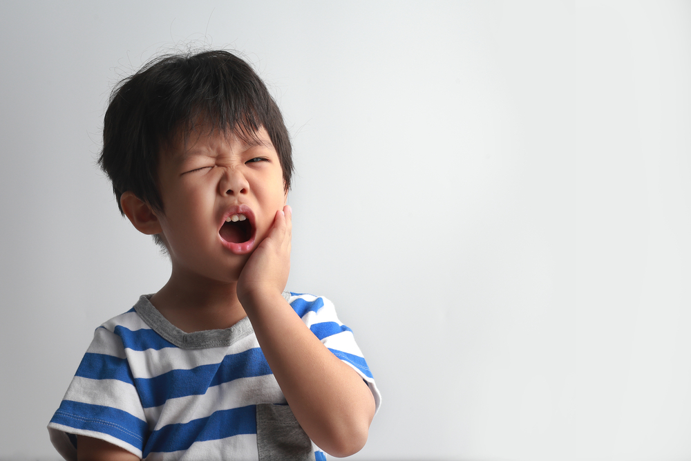 Child-with-tooth-pain-and-his-hands-over-his-cheeks