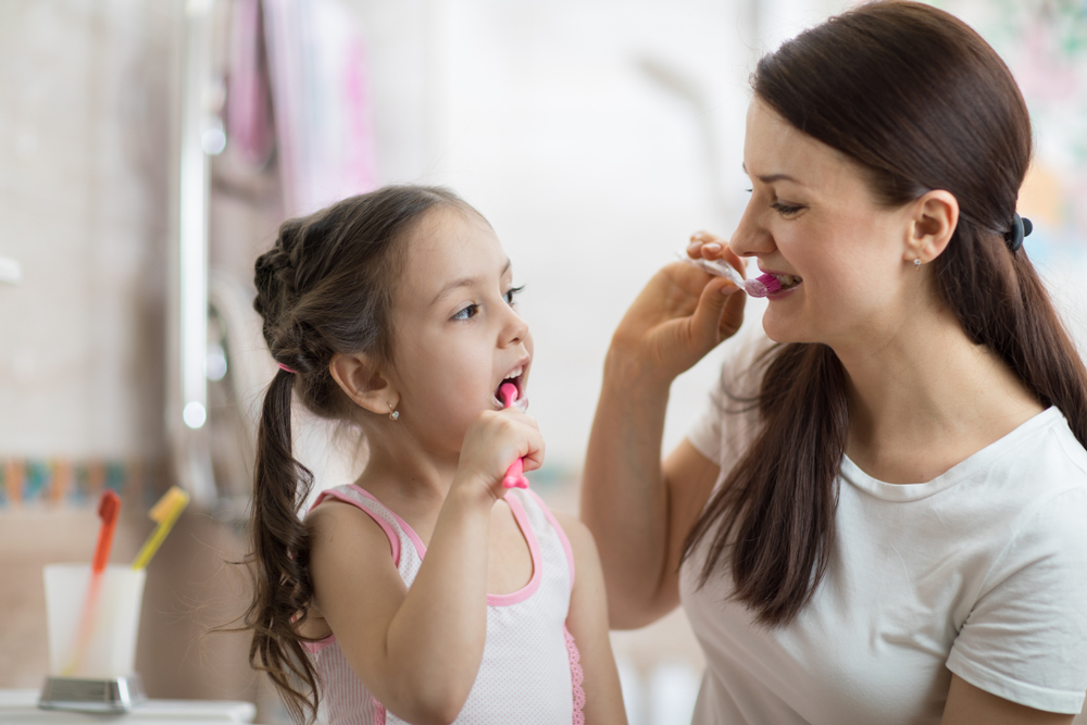 daughter brushes teeth with her mom